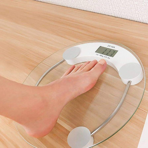 Pèse-personne électronique rond en verre trempé transparent avec écran numérique LCD et capteurs métalliques.