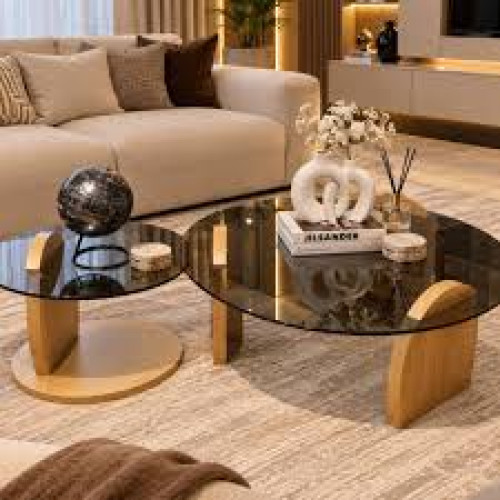 Ensemble de deux tables basses gigognes rondes avec plateau en verre trempé fumé noir et pieds en bois clair posées sur un tapis beige devant un canapé blanc moderne