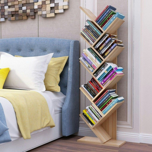 Bibliothèque en bois clair en forme d'arbre remplie de livres à côté d'un bureau blanc avec ordinateur portable