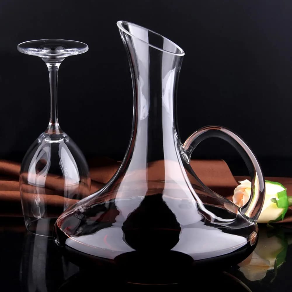 service-table-carafe-cruche-verres-pied-cristal-1-5l Service de table en cristal comprenant une carafe de 1,5 litre avec poignée et six verres à pied remplis de jus de bouye sur une table en bois.