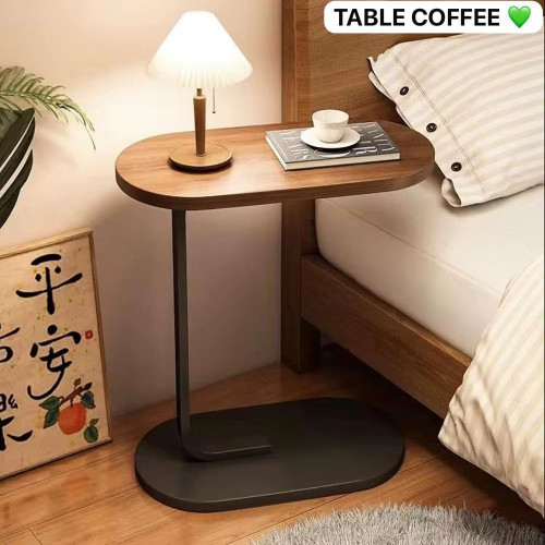 Table d appoint en forme de C avec plateau en bois foncé et pied métallique noir glissée contre un canapé blanc
