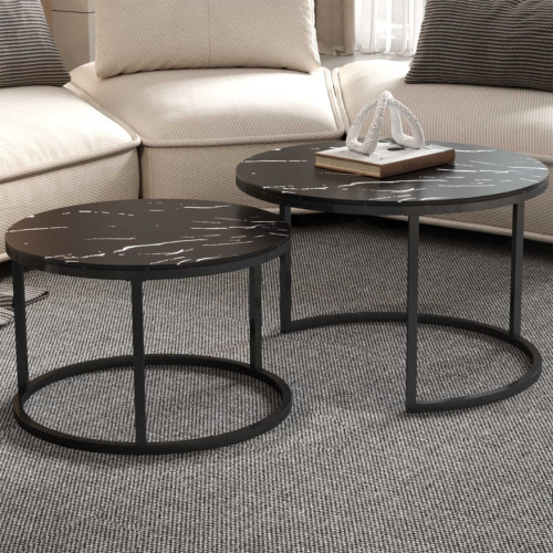 Set de deux tables basses gigognes rondes avec plateaux effet marbre noir et pieds en métal noir devant un canapé.