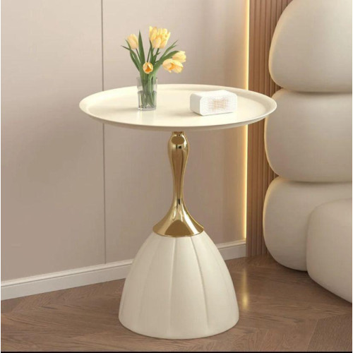 Table d'appoint ronde blanche avec pied tulipe doré miroir à côté d'un canapé beige