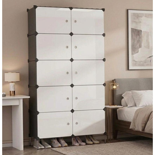 Grande armoire penderie modulable ouverte avec des vêtements suspendus, du linge plié et des chaussures alignées en bas dans une chambre moderne