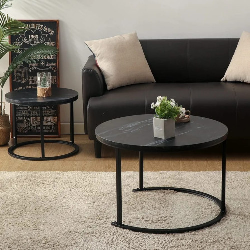 Set de deux tables basses gigognes rondes avec plateaux effet marbre noir et pieds en métal noir devant un canapé.