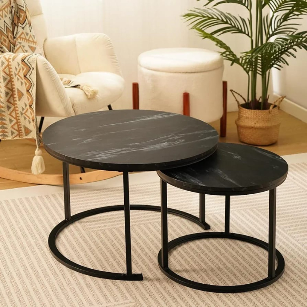 Set de deux tables basses gigognes rondes avec plateaux effet marbre noir et pieds en métal noir devant un canapé.