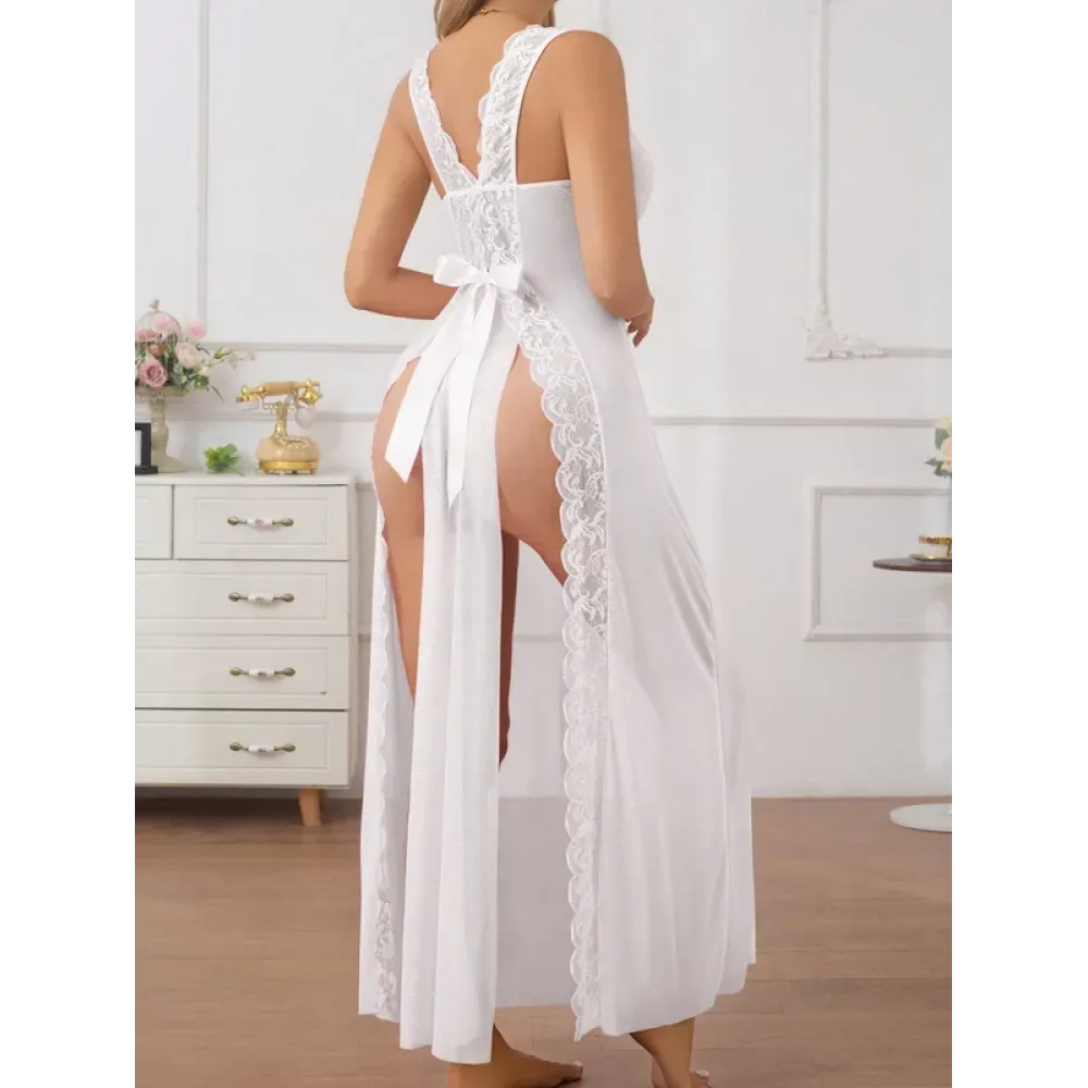 Nuisette longue blanche voile et dentelle Femme debout portant une longue nuisette blanche transparente en voile et dentelle sur le décolleté avec un grand nœud en satin blanc à la taille